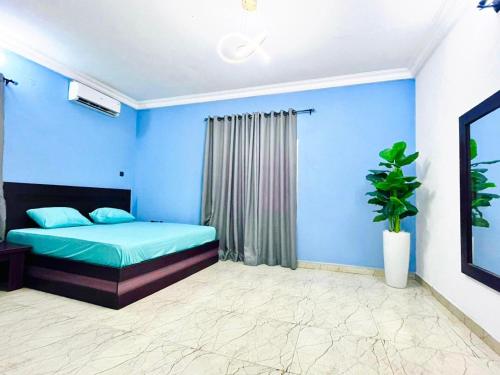 a blue bedroom with a bed and a plant at 2-Bedroom luxury terrace port Harcourt in Port Harcourt