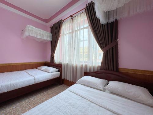 a bedroom with two beds and a window at Nhat Quynh Hotel in Da Lat