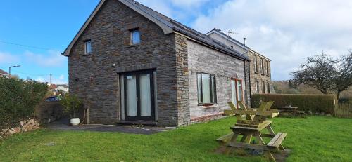 a brick house with a picnic table in the yard at 2 Bed Cottage - sleeps 4 - Garden Parking Wifi in Swansea