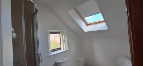 a white bathroom with a window and a toilet at 2 Bed Cottage - sleeps 4 - Garden Parking Wifi in Swansea