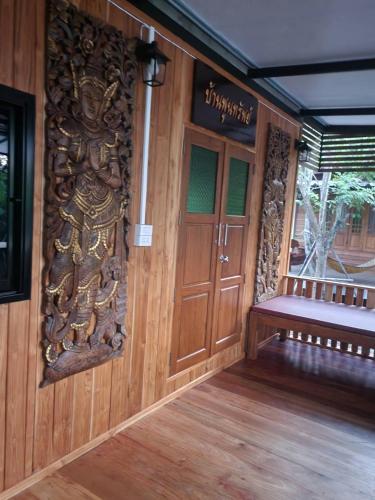 an entrance to a building with a wooden door and a bench at Suk Sabai Homestay in Sukhothai