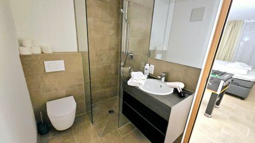 a bathroom with a sink and a toilet and a mirror at TROPICAL ISLAND 23C - Seesicht - Massage - BBQ - Billiard - Tischkicker - Penthouse - Parkplatz in Öhningen