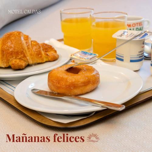 two plates of donuts and orange juice on a table at Motel Caldas in Caldas de Reis
