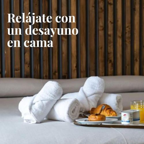 a tray of towels and a plate of food on a bed at Motel Caldas in Caldas de Reis