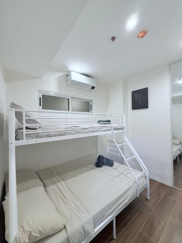 ダバオシティにあるDahlia - Two Bedroom Condo Unit with Verandaの二段ベッド付きの白い部屋の二段ベッド1台分です。