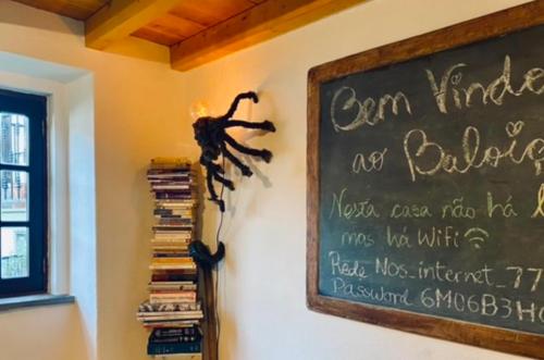 a chalkboard with a spider on a wall with books at Casa do Baloiço in Janeiro de Baixo