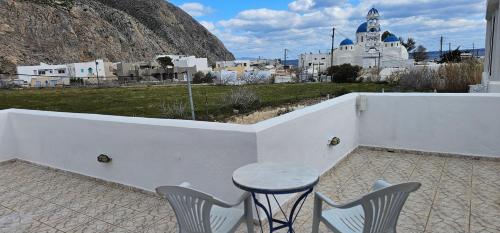 a table and chairs on a patio with a view of a city at Hotel Pleasure Black Beach Perissa Santorini in Perissa