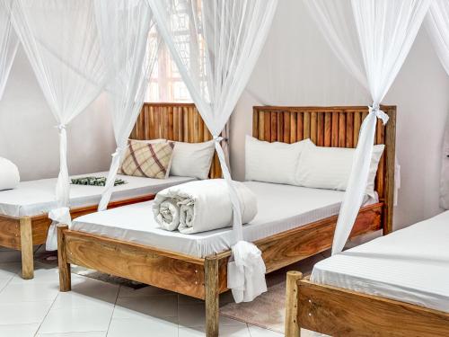 two beds in a room with mosquito nets at Karibu Africa Home in Moshi