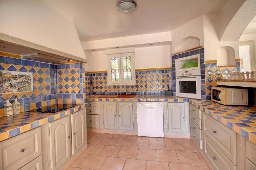 une grande cuisine avec des placards blancs et du carrelage bleu dans l'établissement L hacienda Provençale, à Trans-en-Provence