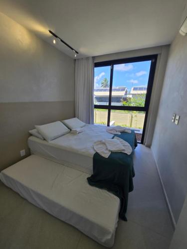 a bedroom with two beds and a large window at Cais Eco Residencia Boutique Beira Mar in Porto De Galinhas