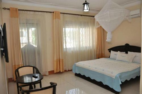 une chambre avec un lit, une table et des fenêtres dans l'établissement Inophine Boutique Hotel Entebbe, à Entebbe