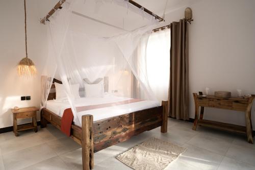 a bedroom with a bed with a mosquito net at African Bungalows in Nungwi