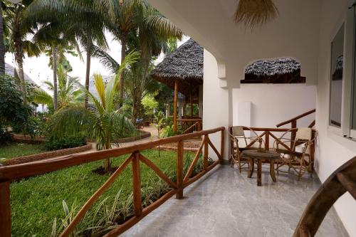 a balcony with a table and chairs and palm trees at African Bungalows in Nungwi