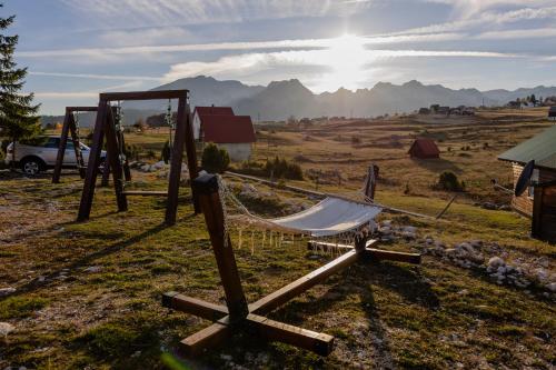 a hammock in a field with mountains in the background at Green Top with jacuzzi in Žabljak