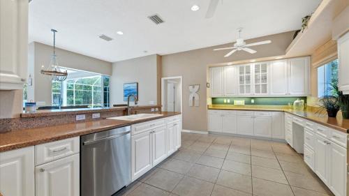 a large kitchen with white cabinets and a ceiling fan at RTC974 in Rotonda West
