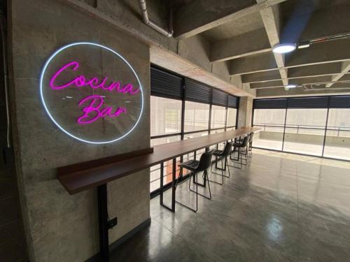 a row of tables and chairs in a room with a neon sign at Lujosa suit cerca del aeropuerto in Pereira