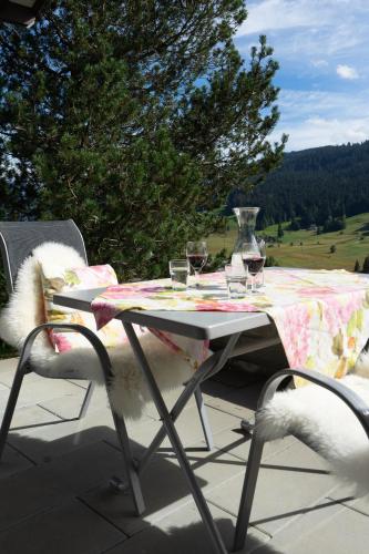 a table with glasses of wine and a vase on it at Steinrüti in Wildhaus