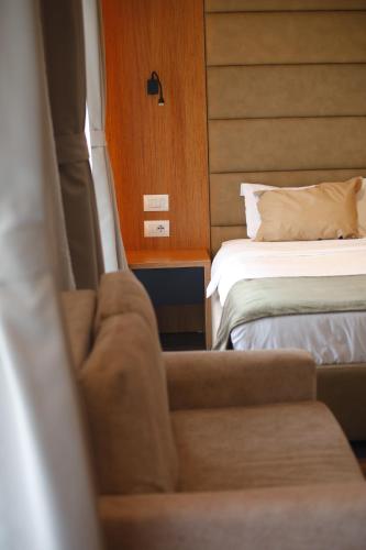 a room with two beds and a couch and a chair at Olivia's Hill Resort in Durrës