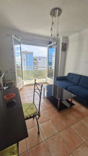 un salon avec un canapé bleu et une table dans l'établissement Au Petit Miramar - Joli T2 face à la mer avec parking, à Saint Cyprien Plage