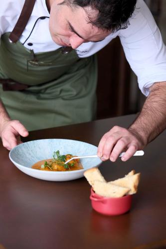a man is eating a bowl of food with a knife at Palheiro Village Resort in Funchal