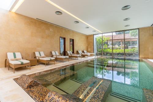 an indoor swimming pool with chairs and a large window at Palheiro Village Resort in Funchal
