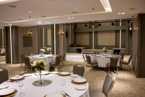 a conference room with tables and chairs and a stage at Anemon Kent Mersin Otel in Çiftlikköy