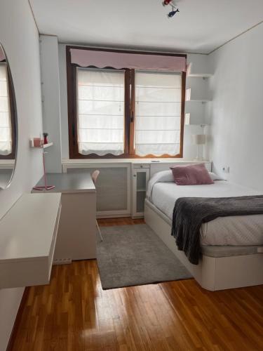a bedroom with a bed and a desk and a window at La Nala in Villaviciosa