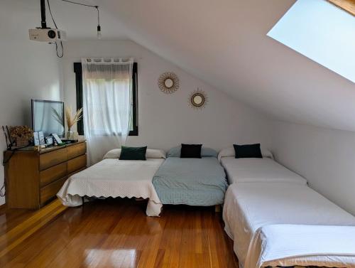 two beds in a room with white walls and wood floors at Chalet con piscina a 5 minutos de la playa in Vilagarcia de Arousa