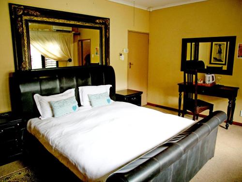 a bedroom with a large bed and a mirror at Thabazimbi Country Lodge in Thabazimbi