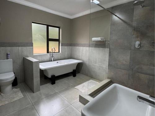 a bathroom with a tub and a sink and a toilet at Thabazimbi Country Lodge in Thabazimbi