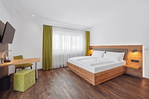 a bedroom with a large white bed and a desk at Hotel Zeppelin in Laupheim
