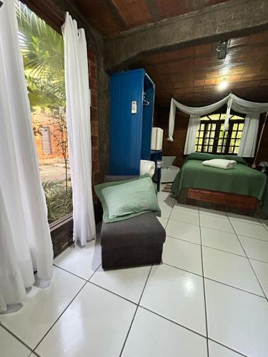 a bedroom with a bed and a ottoman in a room at Pousada do Oasis in Morretes