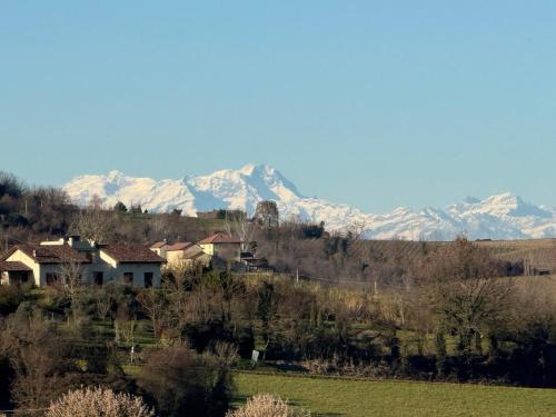 a house in a field with mountains in the background at Corte Arancio your home in the heart of Monferrato in Cella Monte