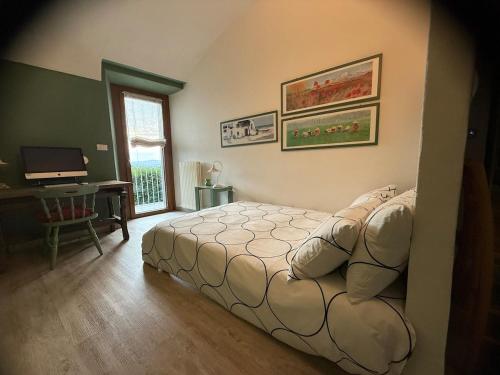 a bedroom with a bed and a desk with a computer at Corte Arancio your home in the heart of Monferrato in Cella Monte