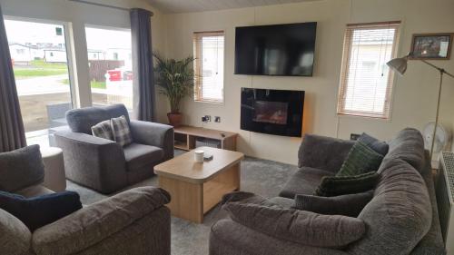 een woonkamer met twee banken en een tv bij Coastal Retreat Lodge in Morecambe