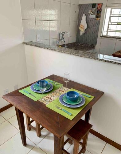 a wooden table with two plates and wine glasses on it at Ap da Serra em Barão de Javary in Miguel Pereira