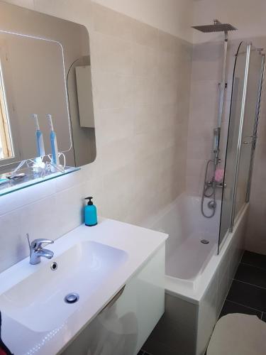 une salle de bain blanche avec un lavabo et une douche dans l'établissement Agréable maison de ville au coeur de Troyes, à Troyes