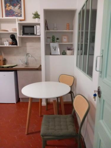 une petite cuisine avec une table et deux chaises dans l'établissement les garrigues, à Nîmes