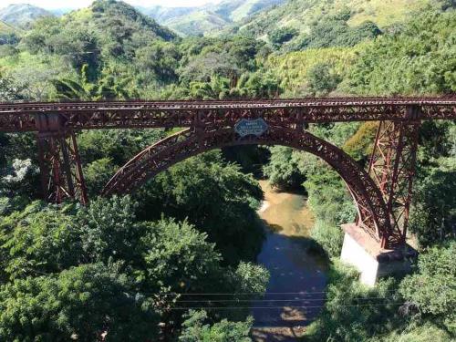 an old bridge over a river with mountains in the background at Ap da Serra em Barão de Javary in Miguel Pereira