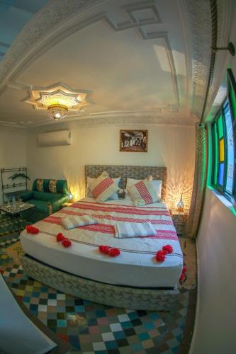 a bedroom with a large bed with red flowers on it at Riad Yamna Fez in Fès