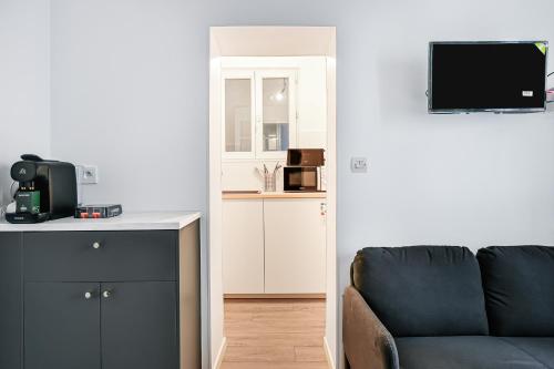 un salon avec un canapé et une télévision dans l'établissement L'Atelier Secret - Batignolles - Métro - Paris 17, à Paris