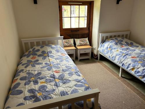 two beds in a small room with a window at Captains Cottage Dover in Wootton