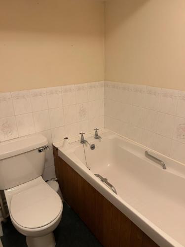 a bathroom with a toilet and a bath tub at Captains Cottage Dover in Wootton