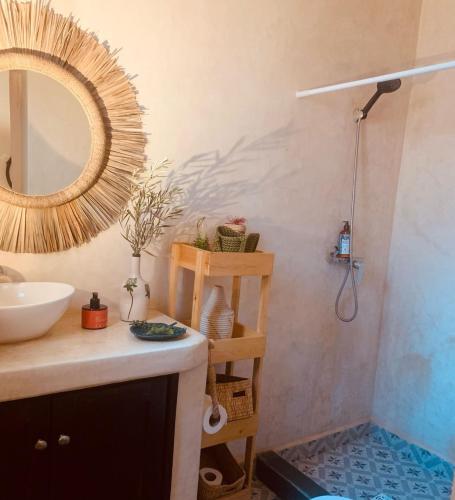 a bathroom with a sink and a shower with a mirror at Maison du soleil in Ghazoua