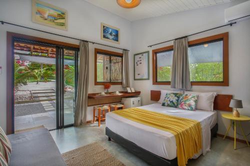 a bedroom with a bed and a desk and windows at Suite Villa Angelim - Barra do Cunhaú - RN in Canguaretama