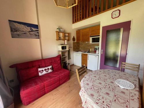 un salon avec un canapé rouge et une table dans l'établissement Studio mezzanine à Jausiers Village, terrasse, idéal 4 pers - FR-1-804-32, à Jausiers