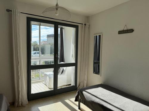- une chambre avec une grande porte en verre donnant sur un balcon dans l'établissement Sol-y-Days Goelette, Agréable appartement en RDC avec parking, proche du centre-ville et de la plage, au Grau-du-Roi
