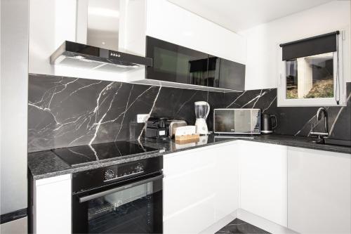 a kitchen with black and white marble counter tops at ACACIAS - Agréable appartement dans maison - Menton - Parking privé in Menton