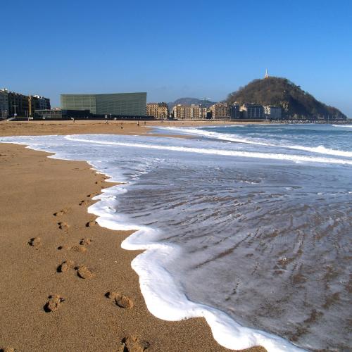 a beach with footprints in the sand and the ocean at Pension Kursaal in Donostia-San Sebastián