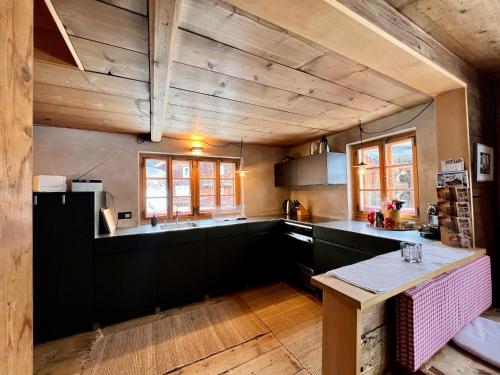 cocina con techos de madera y encimera negra en Alpenlodge Tgèsa Surrein Giassa10, en Sedrun